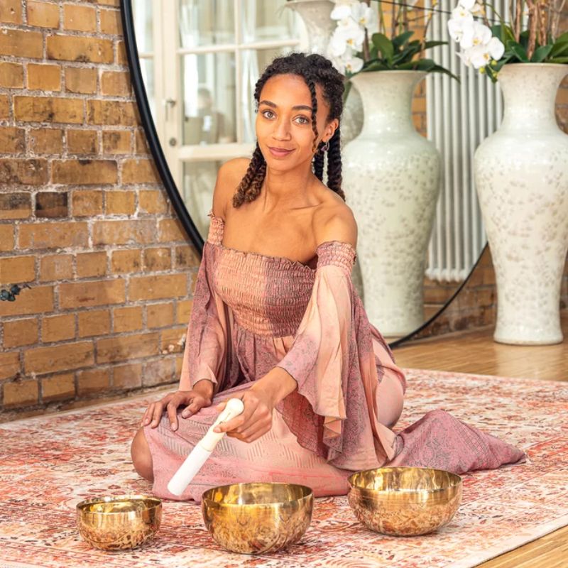 Mujer meditando con varios cuencos tibetanos